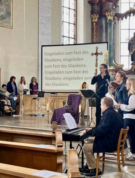 Quelle: Röm.-Kath. Kirchengemeinde Südliche Ortenau Menschen mit und ohne Behinderung im Altarraum, die singen. Eine Band macht Musik und eine Gebärdensprachdolmetscherin übersetzt den Liedtext. Dieser wird auf einer Leinwand angezeigt.